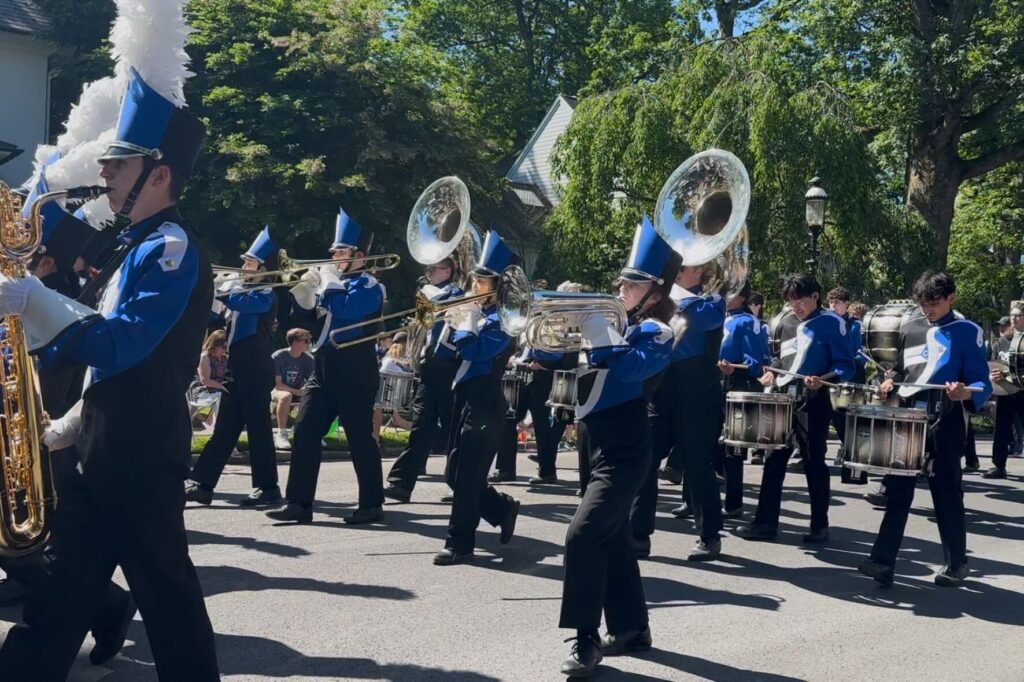 A marching band walks down a street playing their instruments