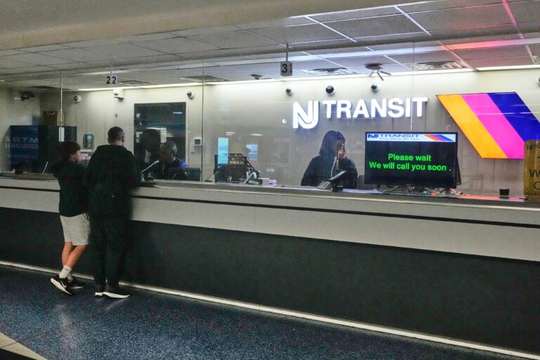 People stand at the train ticket counter of NJ Transit at Penn Station