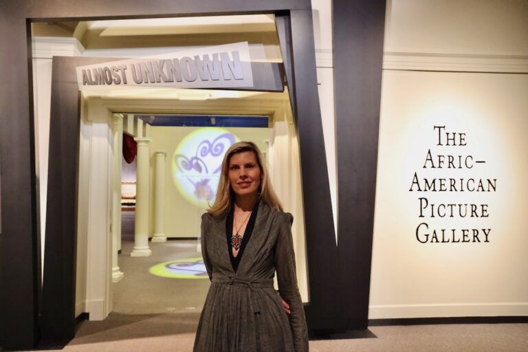 Winterthur Director of Collections Alexandra Deutsch standing in front of exhibit