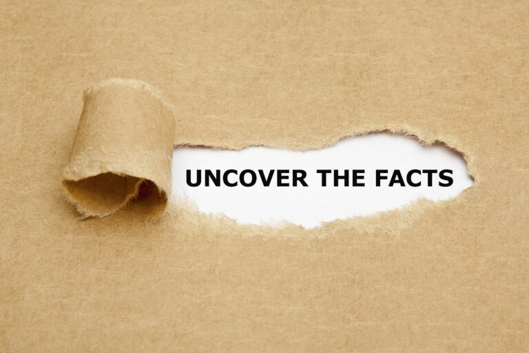 Uncover The Facts appearing behind torn brown paper.
** Note: Shallow depth of field