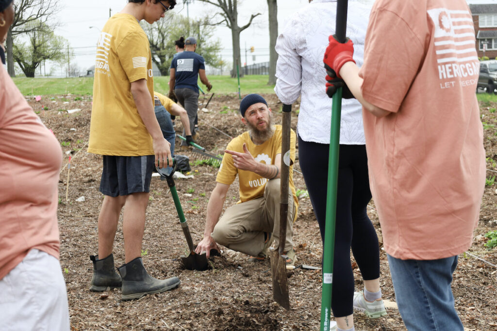Michael Peterman shows Heroic Gardens volunteers how to dig holes