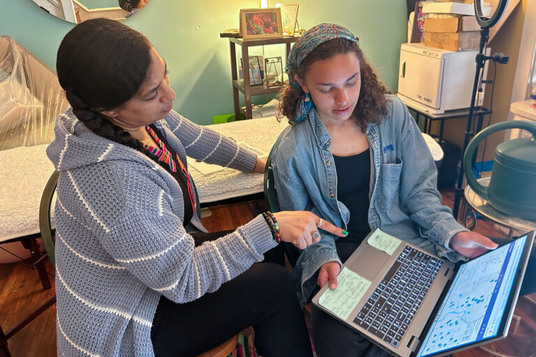 Tina Alishia Brown and Jendaiya Hill looking at a laptop computer together