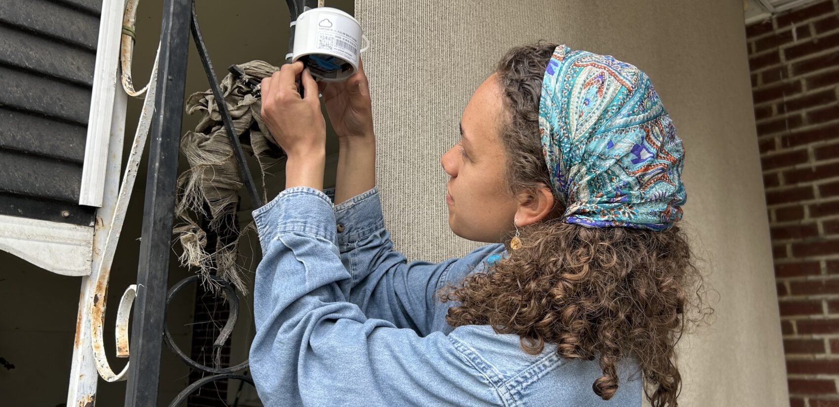 Jendaiya Hill is working on a device attached to the railing on her front porch