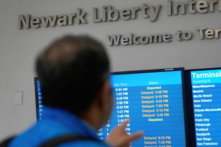 A display shows the status of flights at Newark Liberty International Airport