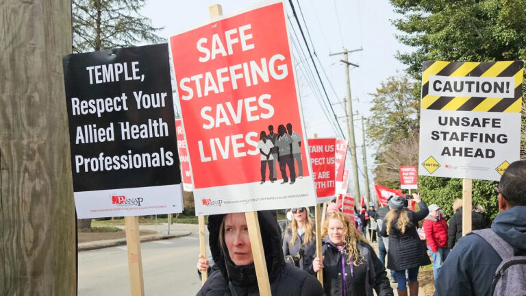 Nurses and technicians in Philadelphia hold signs regarding complaints over staffing