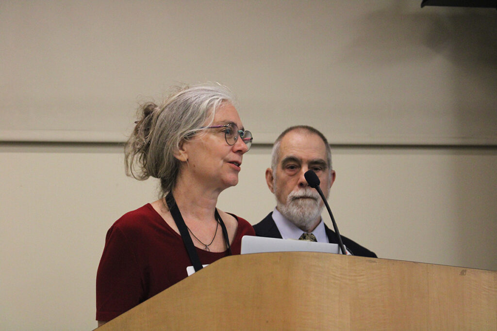 A woman speaks into a microphone at a podium