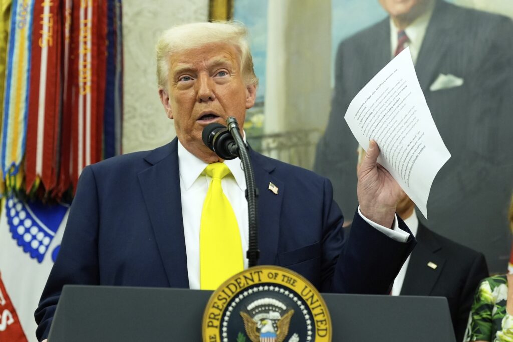 Trump 100 Days President Donald Trump holds a document with notes about Kilmar Abrego Garcia as he speaks with reporters in the Oval Office of the White House, April 18, 2025, in Washington.