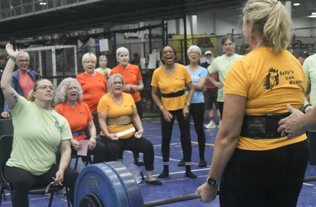 Sally’s Iron Mustangs cheer on teammate Kathy Kirk