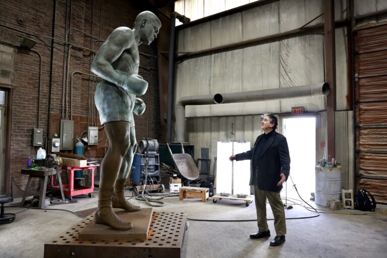 Zenos Frudakis stands beside his 10-foot-tall statue of Muhammad Ali