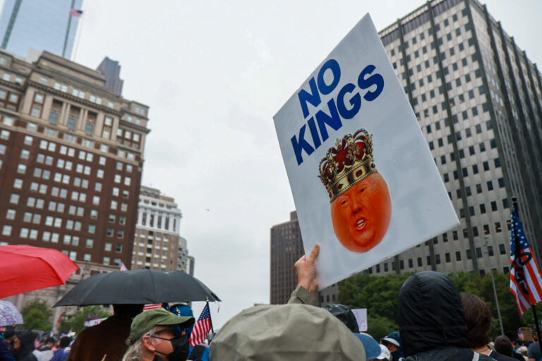 a sign says NO KINGS with Donald Trump's face