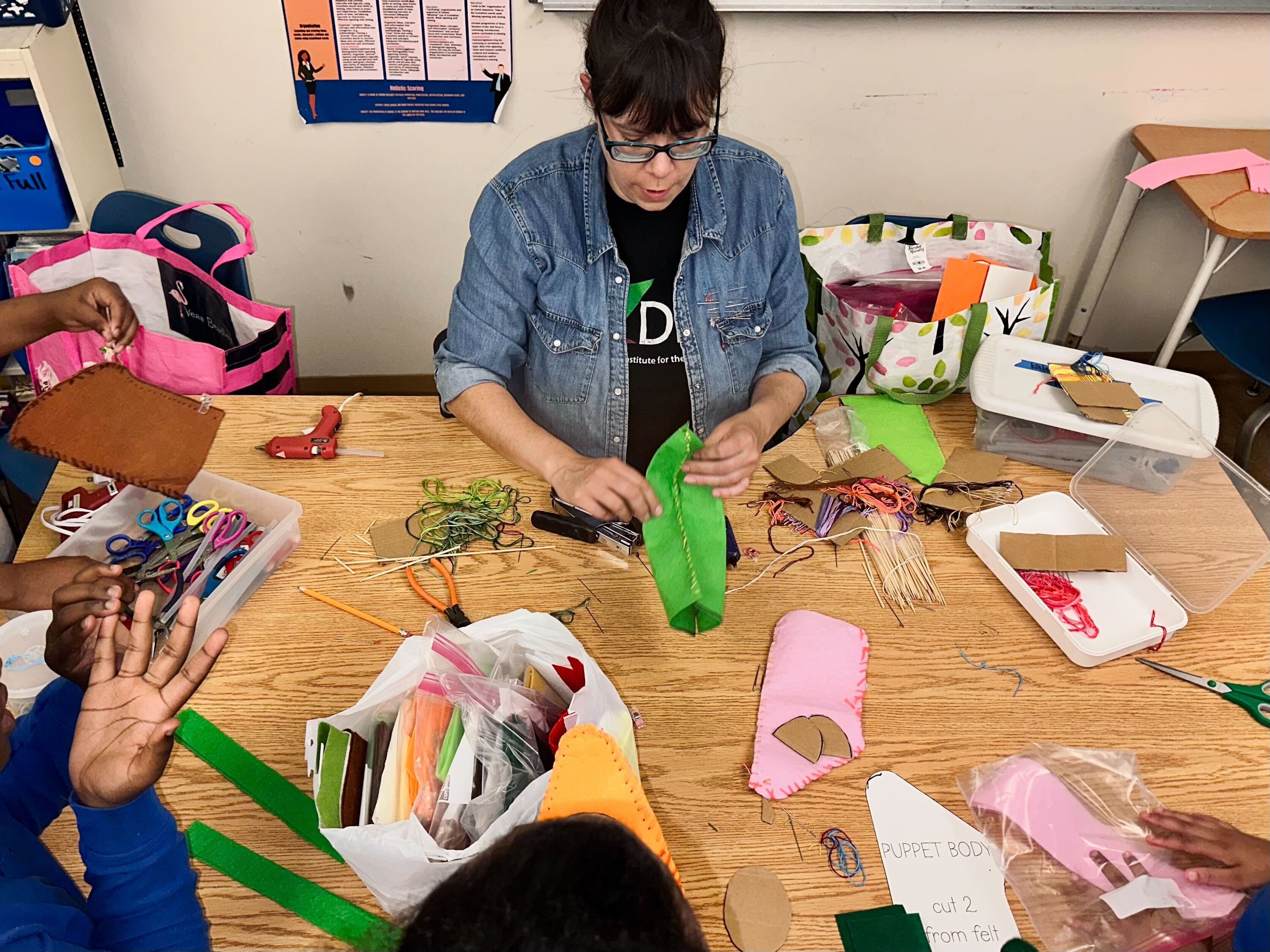 Kate Testa helps three students with puppets