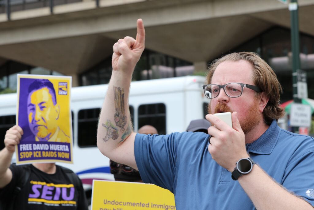 A man speaking into a megaphone at the protest