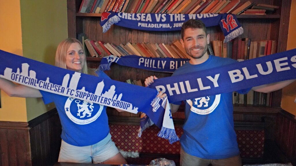 2 Chelsea fans hold up flags for their team