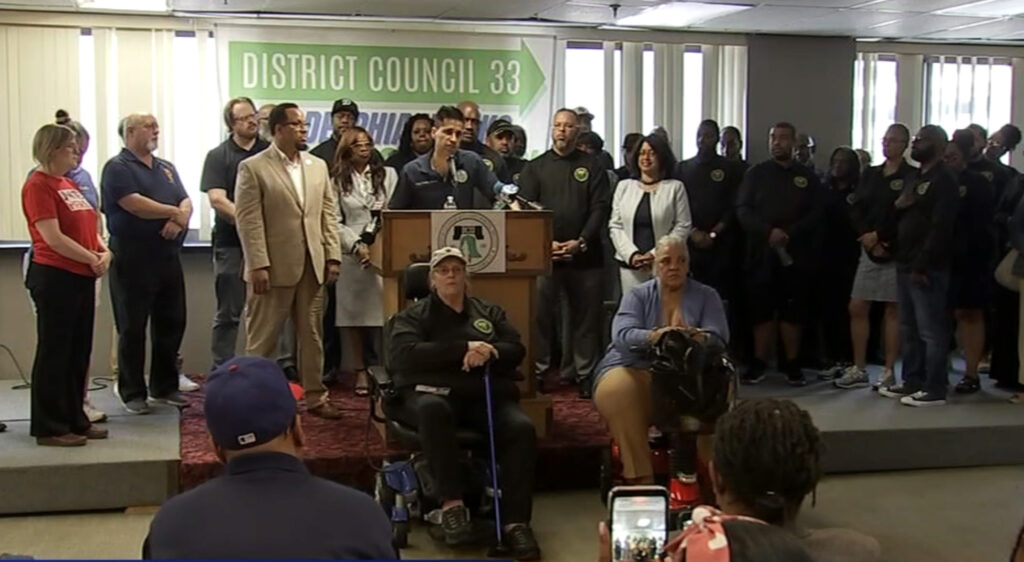 council_33_strike A number of union workers who work for Philadelphia stand behind a podium as they announce their vote to strike amid contract negotiations