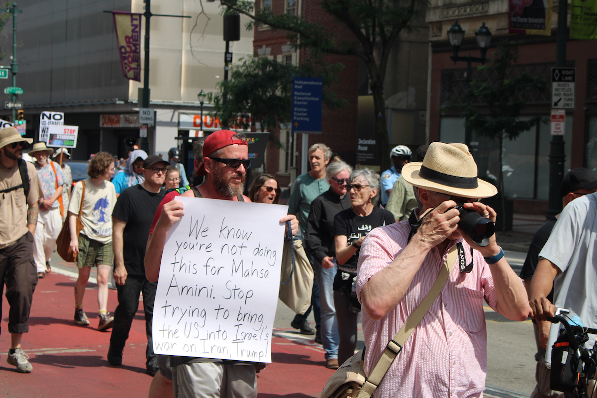 A man holds a sign as people march in Philadelphia, calling for the U.S. to not become involved in the Israel-Iran war