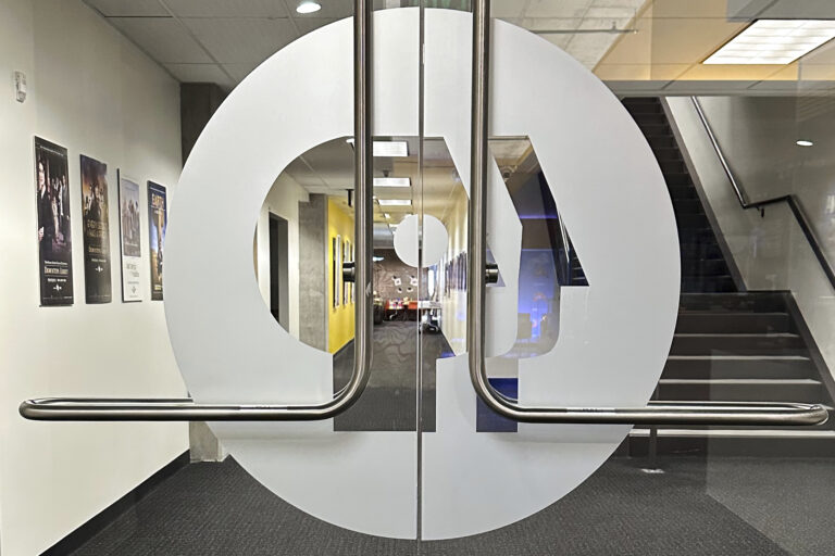 The PBS logo is on interior double glass doors leading into an office