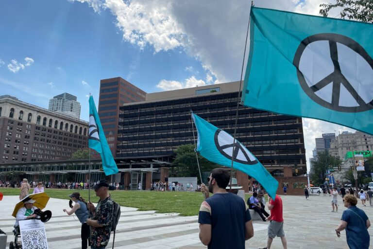 People rally against U.S. involvement in the Iran-Israel war in Philadelphia, holding flags with the symbol for peace on them
