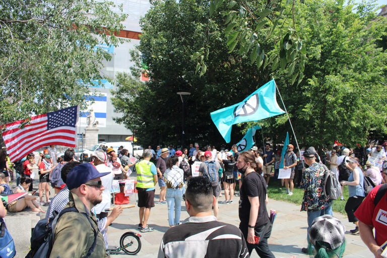 People rally against U.S. involvement in the Iran-Israel war in Philadelphia, holding flags with the symbol for peace on them