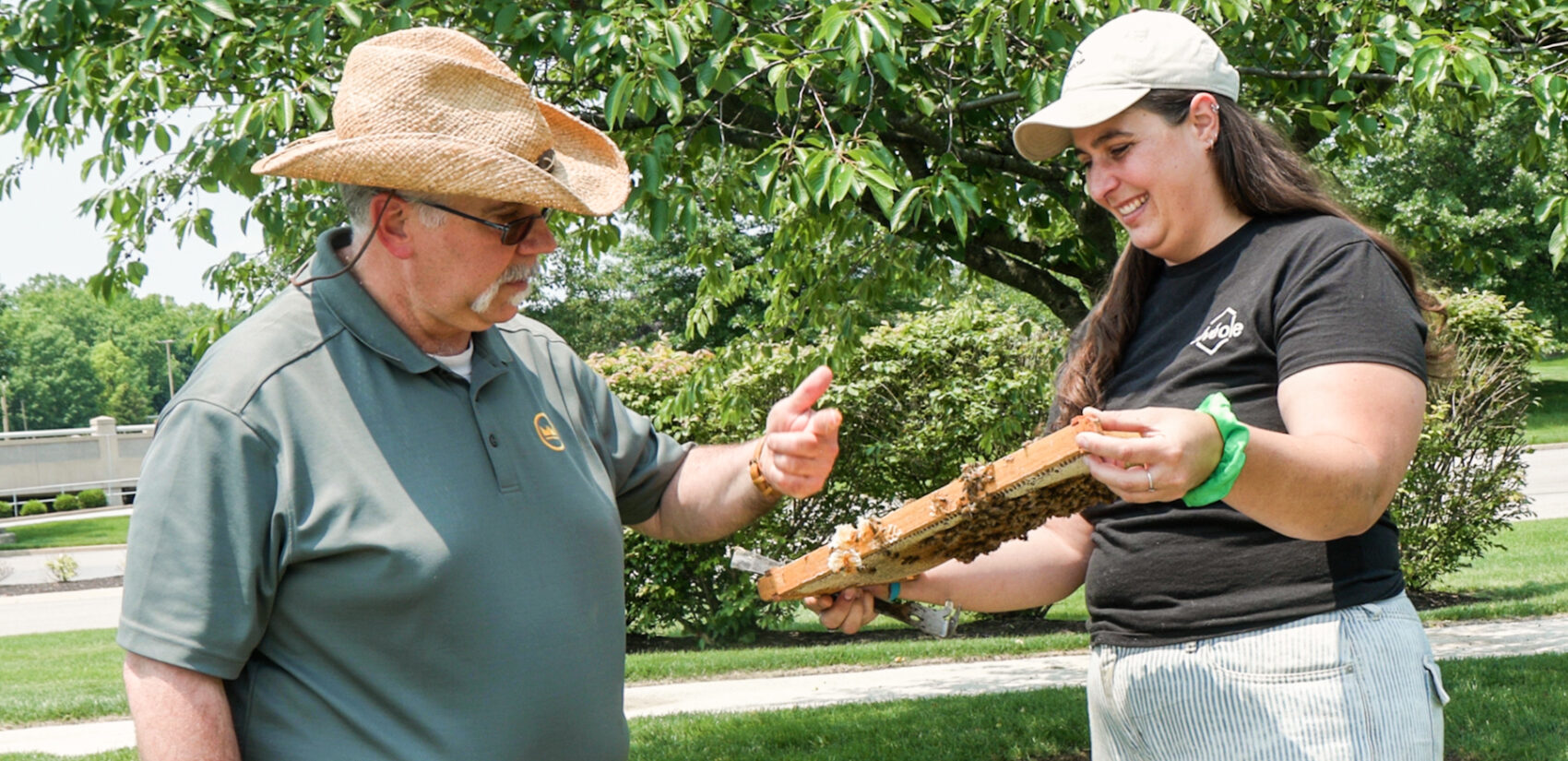 Christopher Basler gets a finger of honey from a hive held by Kristen Rydberg