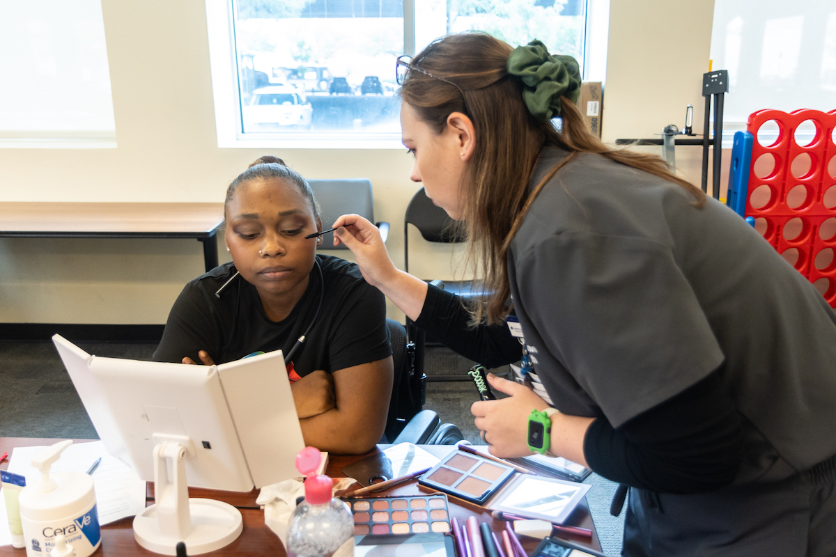 Lucy Watts Stidfole applies eye shadow to a patient