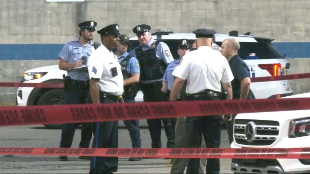 16968837_070525-wpvi-south-philly-mass-shooting-scene-img A group of Philadelphia police officers gather in a parking lot behind caution tape