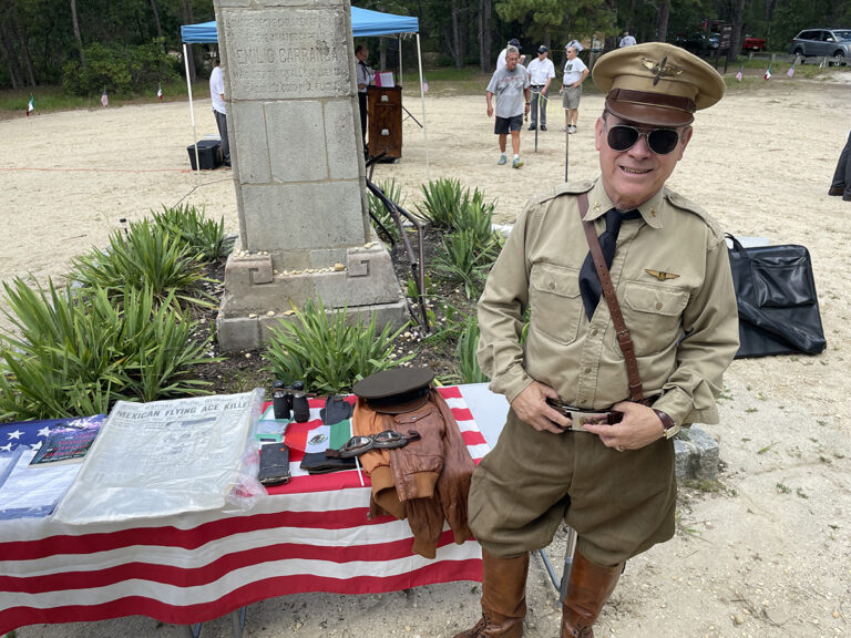Actor Peter Titus stands next to items related to Emilio Carranza that he has collected while dressed like an fighter pilot from the era