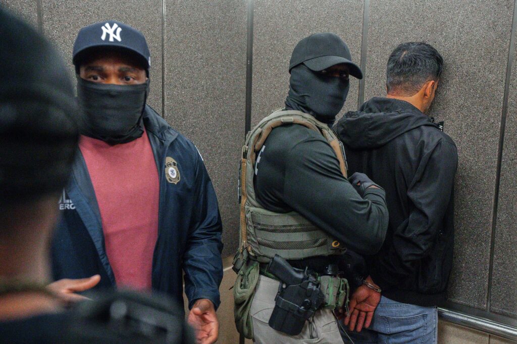 Immigration and Customs Enforcement agents escort a detained immigrant into an elevator