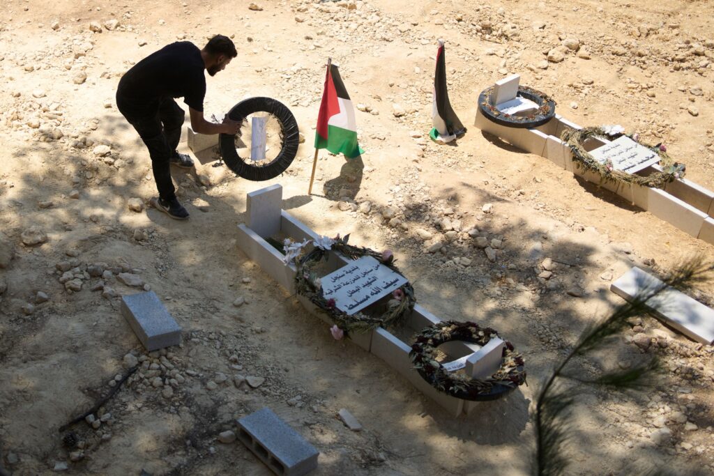 Palestinian-American-grave-2025-07-21 a man tidies the graves of Palestinian-American Sayfollah Musallet and Mohammed al-Shalabi
