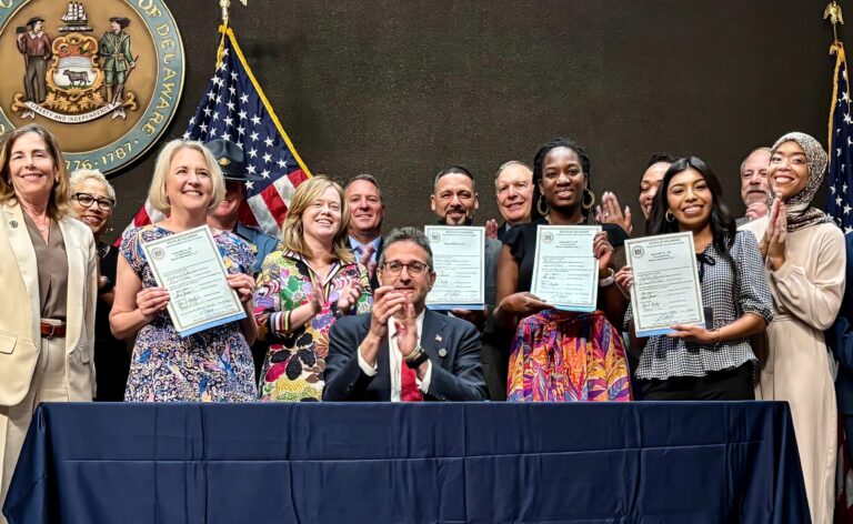 Delaware state lawmakers holding signed ICE bills