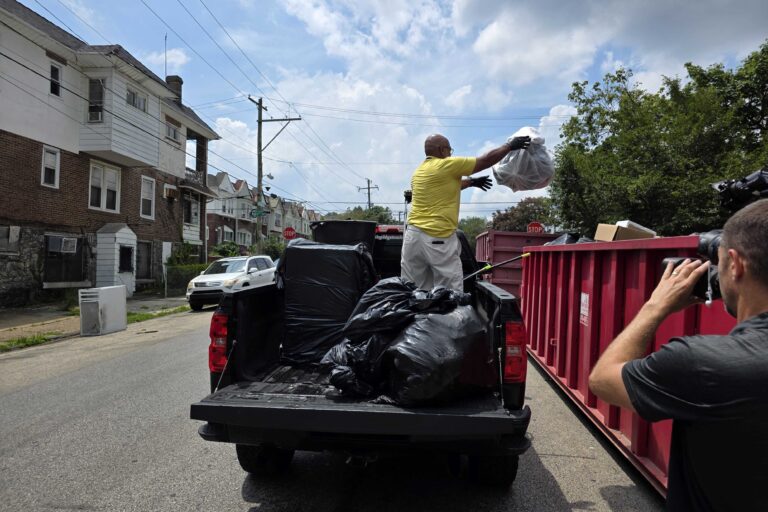 Frank Tingle throws trash into dumpster
