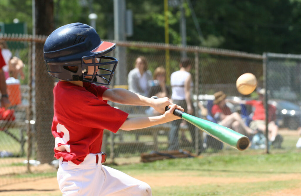Youth League Batter A child baseball player hits a ball with his bat