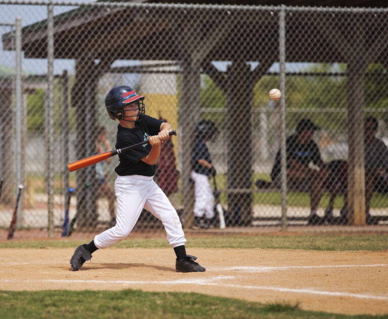 A Little League baseball player swings a bit