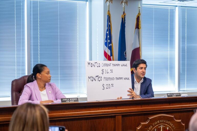 Montgomery County Commissioner Neil Makhija holds up a sign showing the previous starting minimum wage for county employees