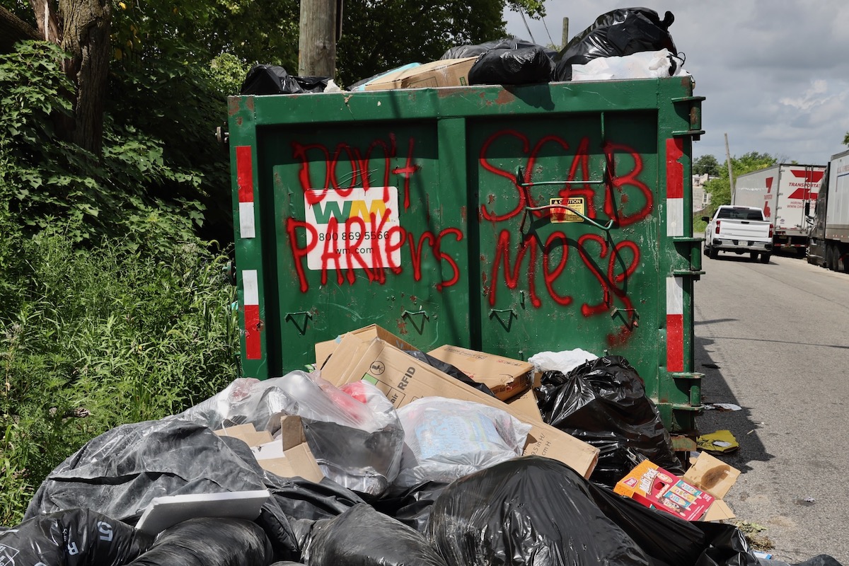 Overflowing dumpster on Wyalusing Avenue is marked with graffiti