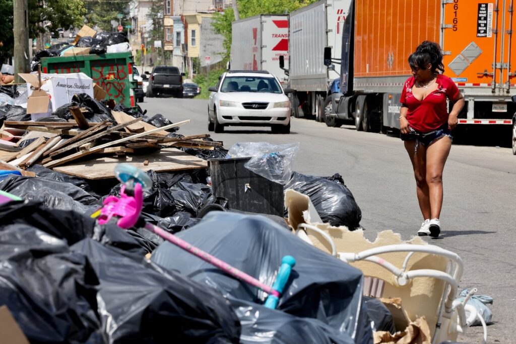 A pedestrian walking around trash mound along Wyalusing Avenue