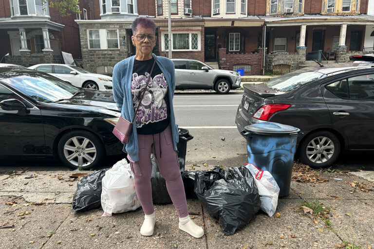 A woman stands near bags of trash in Philadelphia amid a city workers strike.