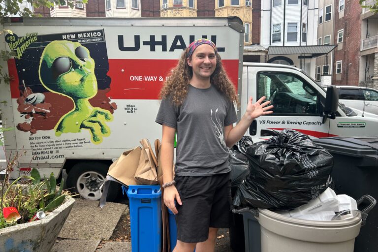 A man stands in front of trash and recycle cans, saying he supports the sanitation workers' strike in Philadelphia.