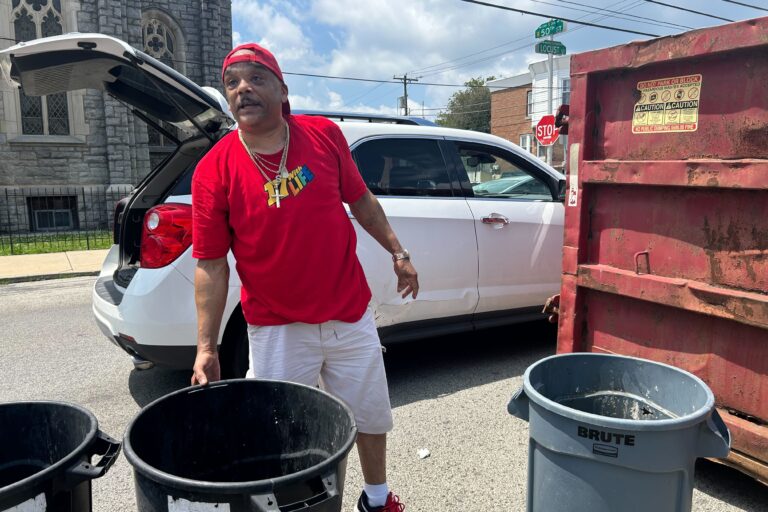 A man gathers trash cans near a dumpster amid the Philadelphia city workers strike.
