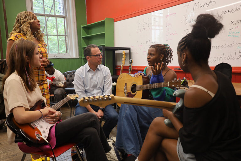 Pennsylvania Gov. Josh Shapiro listens as he sits with students holding guitars