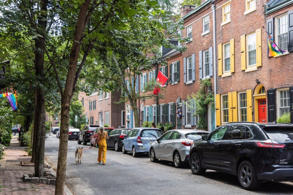 Homes on South Camac Street in Philadelphia. (Kimberly Paynter/WHY) A woman walking a dog down the middle of a quiet city street