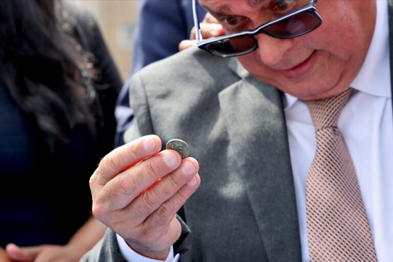 A man closely inspects a coin in his hand