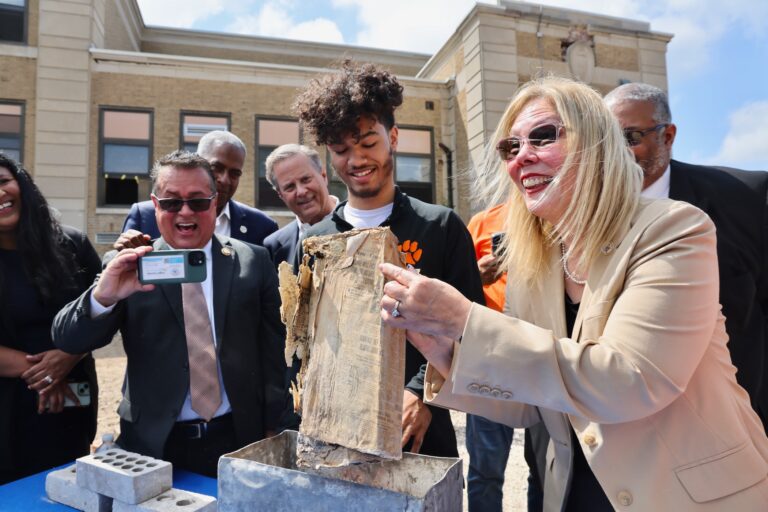 Nilsa Cruz with students holding up an item from the time capsule