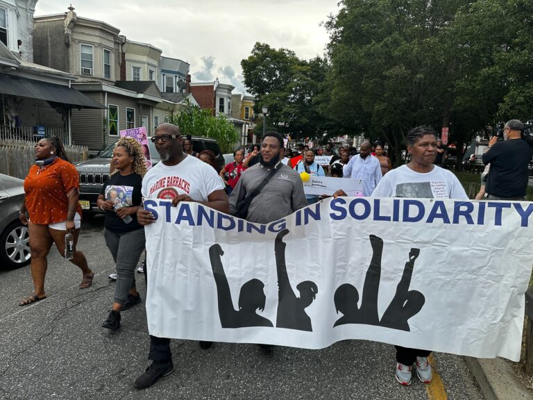 Dozens marching through Camden holding a banner reading STANDING IN SOLIDARITY