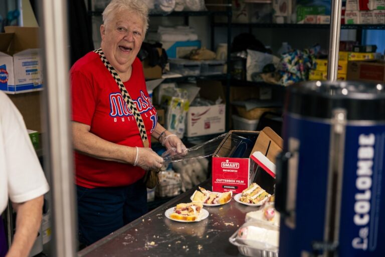 Kathy McGovern smiles while cutting and wrapping cake slices