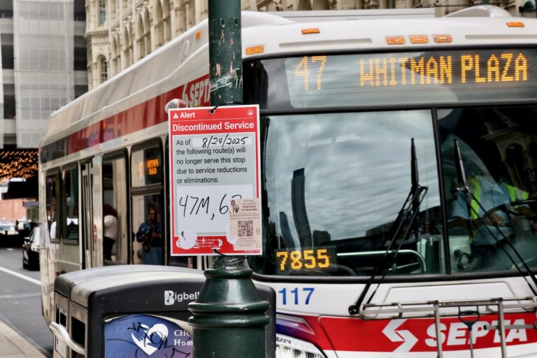A bus pulls up to the curb, and a sign on a lightpole says that the line will be discontinued due to service reductions.