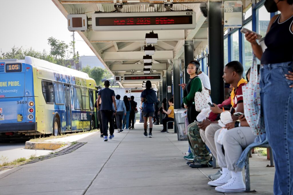 Many people waiting in the outdoor bus terminal