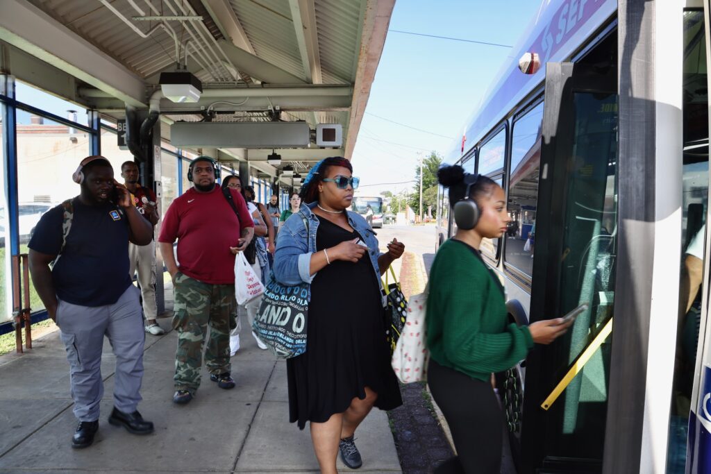 A group of people line up to get onto a bus