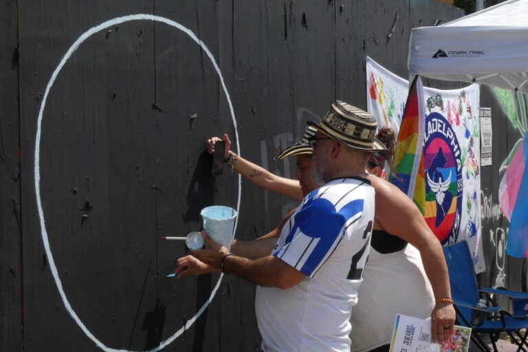 Two people chalk a wall with art