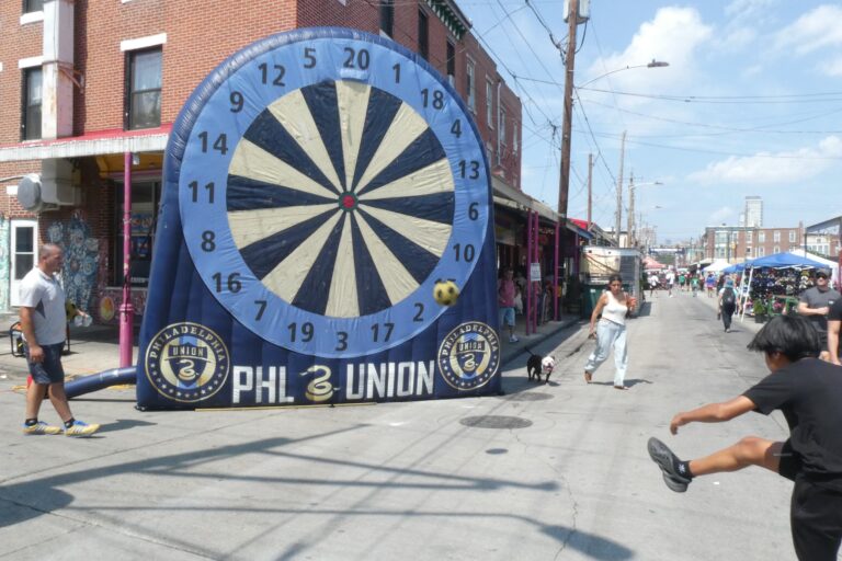 a kid takes a soccer shot at an inflatable dartboard