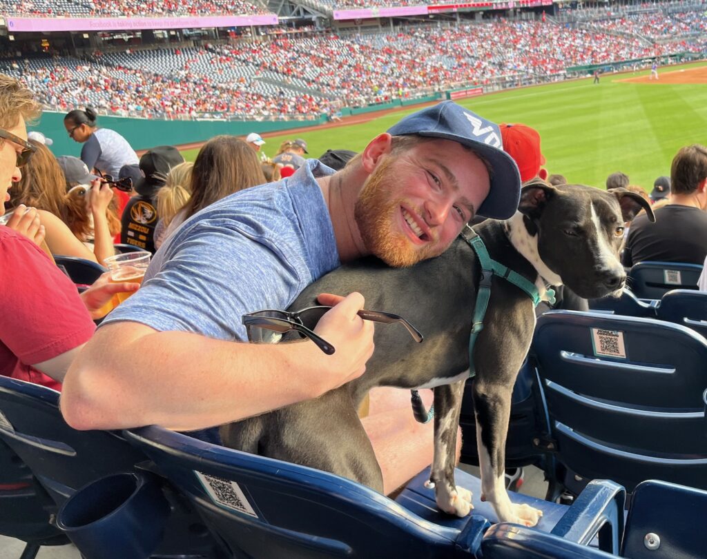 adam-fishbein-2025-08-13-1 Adam Fishbein with a dog in the stands at a baseball game